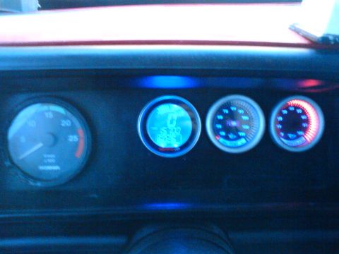 1989 Ford Bronco - A close-up view of a vehicle's dashboard displays illuminated gauges with blue and red lighting.
