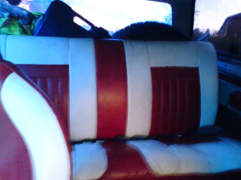 1989 Ford Bronco - The interior of a vehicle features a red and white striped bench seat with a view of the rear window and some items in the back.