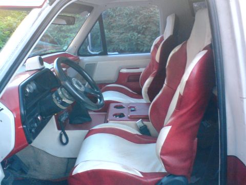 1989 Ford Bronco - The interior of a vehicle features custom red and white striped seats and matching door panels.