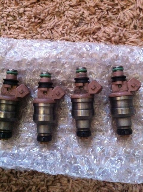 1991 Eagle Talon - Four fuel injectors are laid out on bubble wrap, with a carpeted surface visible in the background.