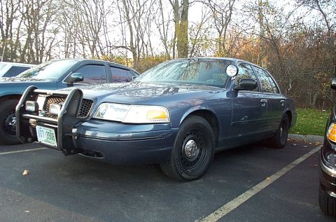 1991 Ford LTD Crown Victoria - Police car with push bumper and light bar parked in a lot.