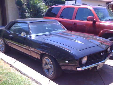 1968 Ford Mustang - A black 1969 Chevrolet Camaro is parked in a driveway next to a red SUV.