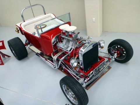 1969 Lincoln Continental - A custom red hot rod with a powerful exposed engine and a white interior is displayed indoors.
