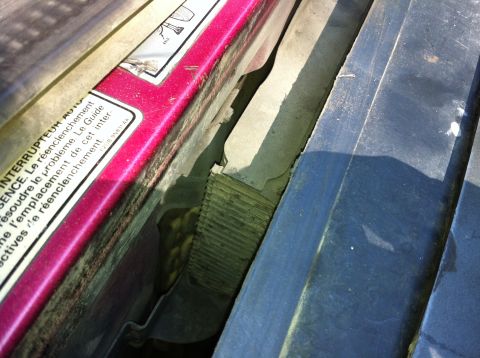 1992 Ford F-150 - Looking down the gap between a burgundy radiator core support and the black hood, showing dust-caked radiator or condenser fins and a Frenc…