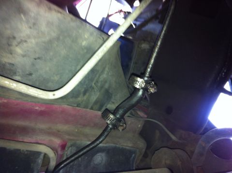 1992 Ford F-150 - Under-hood view down into a burgundy engine bay, showing rubber heater or coolant hoses secured with worm-gear clamps where they pass a pai…
