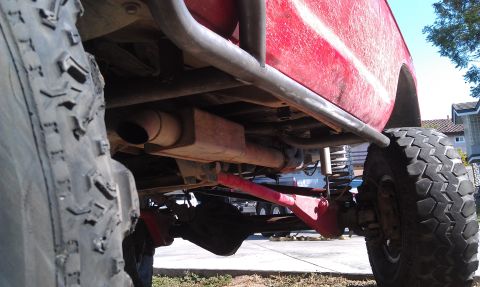 1978 Ford Bronco - Close-up view of the undercarriage and suspension of a modified red off-road vehicle.