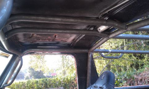 1978 Ford Bronco - Custom roll cage installed inside a vehicle, with a view of the exterior through the windows.