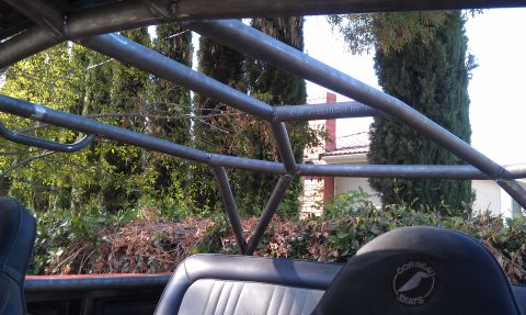 1978 Ford Bronco - The interior of a vehicle is shown with a custom roll cage and a Corbeau seat visible.