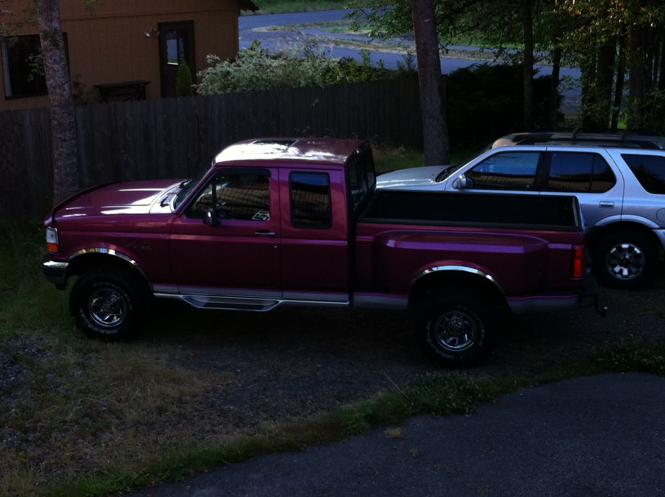 Red Ford F-150 pickup truck parked next to a silver SUV