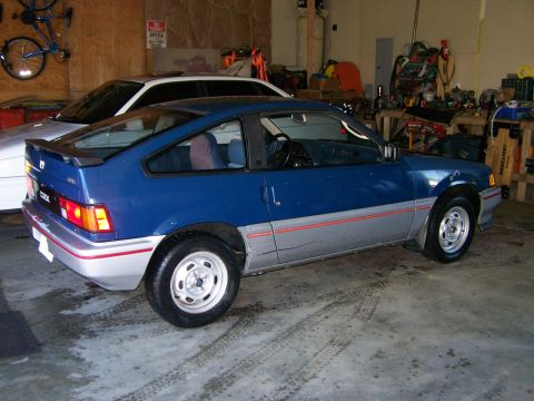 1988 Suzuki Samurai - A blue and silver Honda CRX is parked in a garage, with another vehicle visible behind it.