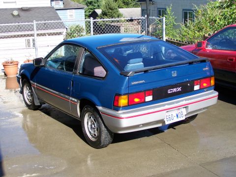 1988 Suzuki Samurai - A blue Honda CRX is parked on a wet driveway next to a red vehicle.