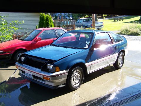 1988 Suzuki Samurai - Two cars are parked in a driveway, one with its hood open, reflecting sunlight.