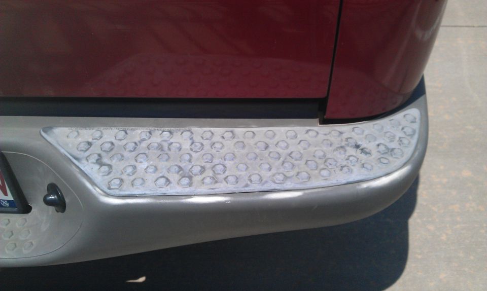 Close-up of a worn rear bumper step pad with hexagonal pattern