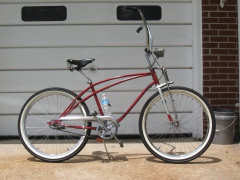1994 Ford Bronco - A red cruiser bicycle with chrome accents and white-wall tires is parked outdoors.