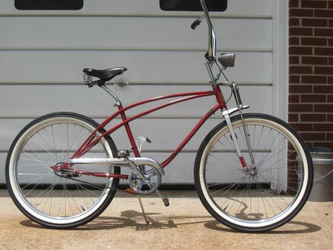 1994 Ford Bronco - A red cruiser bicycle with whitewall tires and a chrome chain guard is parked in front of a garage.