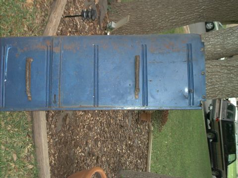 1971 Ford Bronco - A blue tailgate lies on the ground, with a vehicle partially visible in the background.