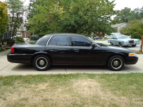 2001 Ford Crown Victoria - Side profile of a black 2001 Ford Crown Victoria parked in a suburban driveway.