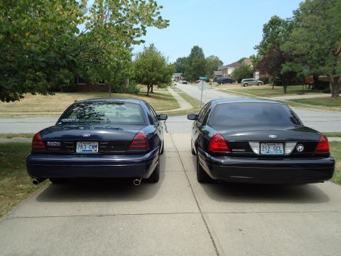 2001 Ford Crown Victoria - Two Ford Crown Victorias are parked side-by-side in a suburban driveway.