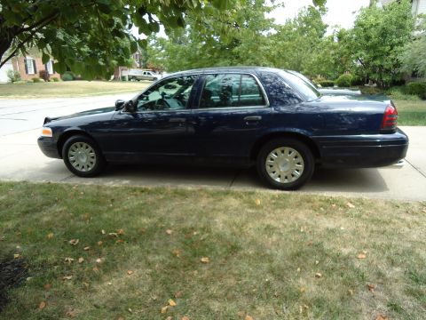 2001 Ford Crown Victoria - Side profile of a dark blue 2001 Ford Crown Victoria sedan parked on a suburban street.