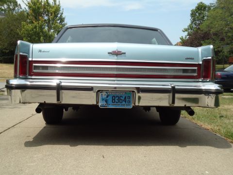 2001 Ford Crown Victoria - Light blue sedan's rear end with a chrome bumper and a Kentucky license plate. A second car is visible on the right.