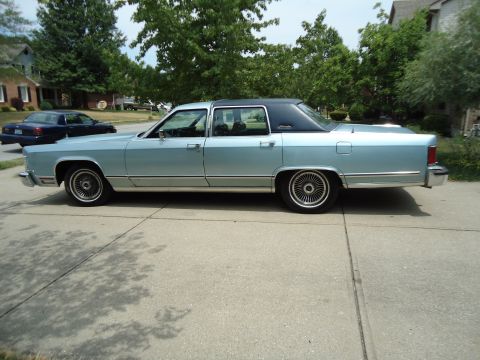 2001 Ford Crown Victoria - A light blue 1979 Lincoln Continental sedan with a black vinyl roof is parked on a driveway, with another dark sedan visible in the backgro…