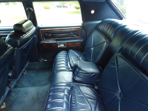 2001 Ford Crown Victoria - The interior of a car shows plush blue leather seats and wood accents on the door panel.