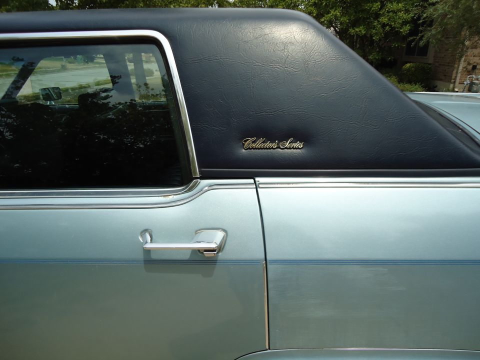 Side view of light blue car's rear quarter panel with black vinyl top and 'Collector's Series' emblem