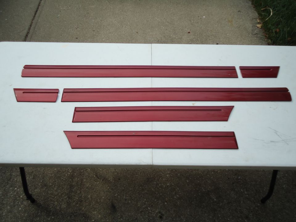 Several red trim pieces laid out on a white surface