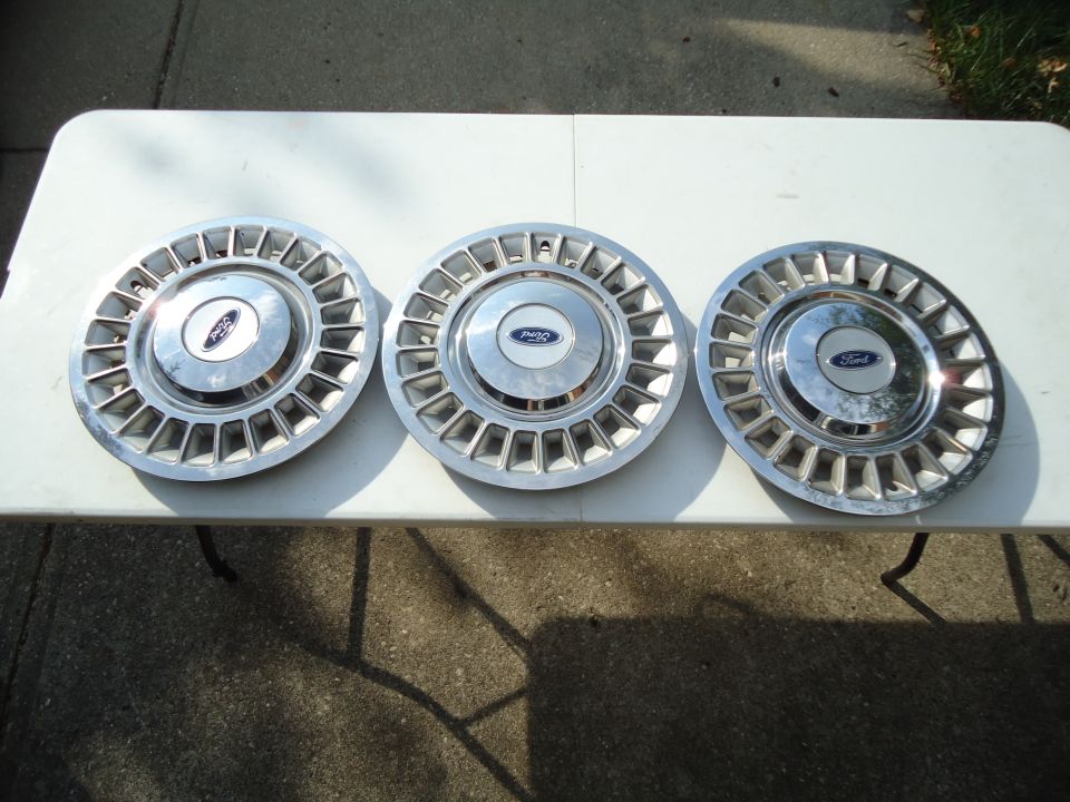 Three Ford hubcaps with chrome finish and rectangular cutouts