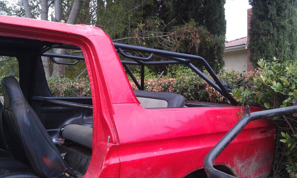red SUV with black roll cage, interior visible, parked near bushes and trees. Supermotors.net logo in corner