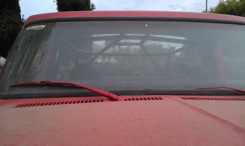 1978 Ford Bronco - Interior view of a red vehicle with a visible roll cage and a Magnaflow sticker on the windshield.