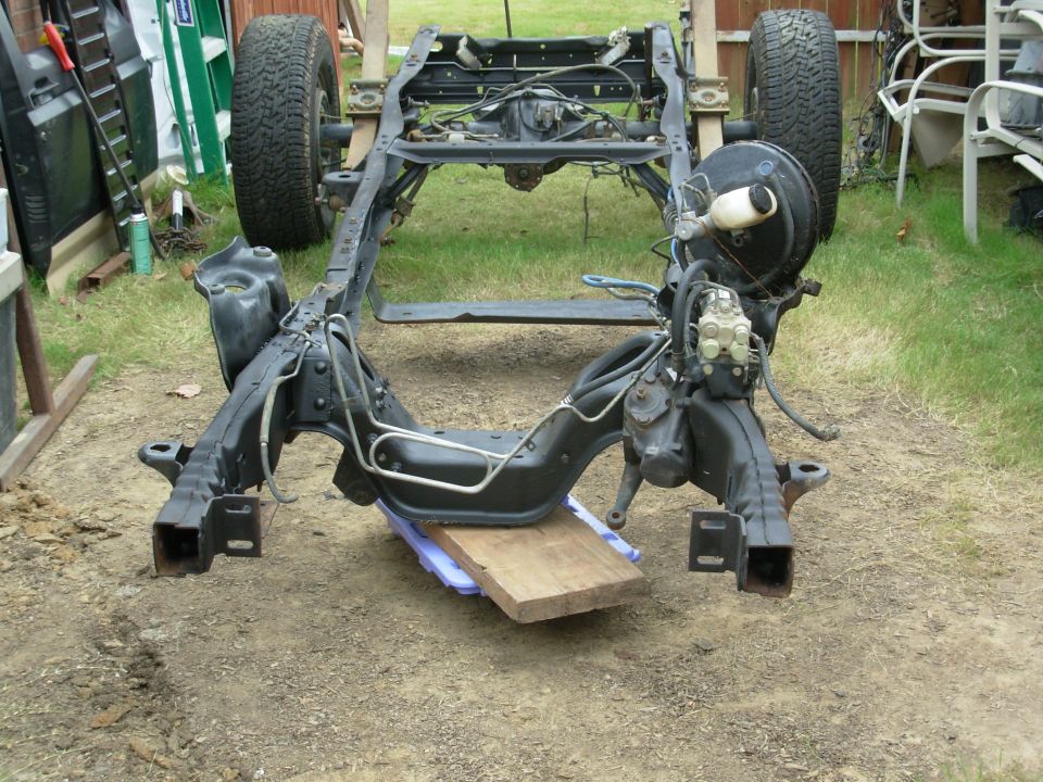 I manhandled the frame onto the loose rear axle (OK, I DROPPED IT), bolted up the fronts of the springs, set the engine crossmember onto a furniture dolly, and reverse-rickshawed it into my work area.