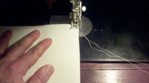 1900 Ford C-350 (Centurion Conversions) - A hand guides white fabric through a sewing machine, with threads visible.