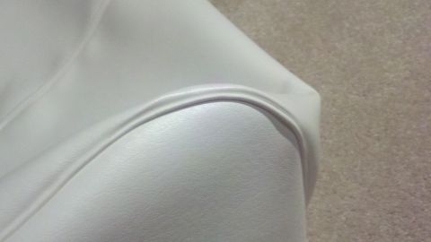1900 Ford C-350 (Centurion Conversions) - Close-up of white interior upholstery, showing a curved seam and textured surface.