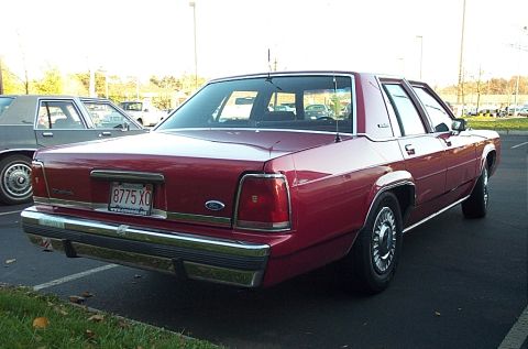 1991 Ford LTD Crown Victoria - Rear view of a red 1991 Ford Crown Victoria LTD parked in a lot next to another car.