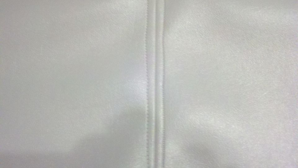 Close-up of white stitched upholstery with a vertical seam