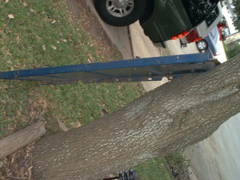 1971 Ford Bronco - A blue metal panel is propped against a tree, with vehicles in the background.