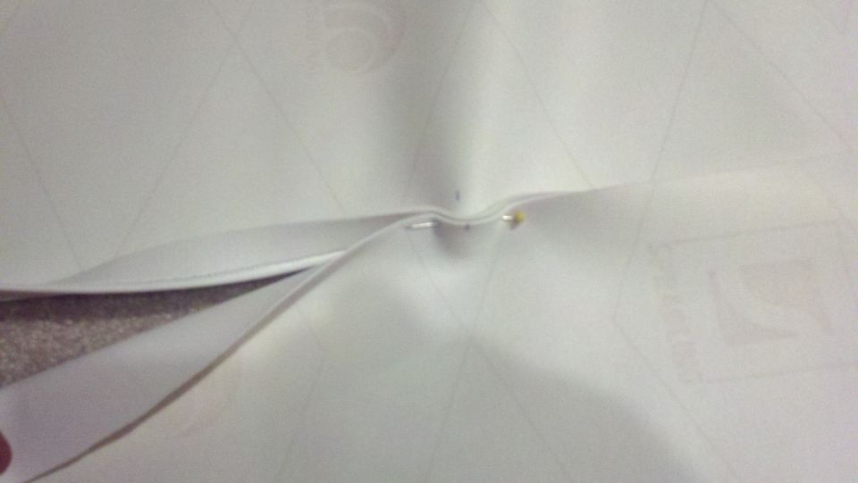 White document with faint grid lines and a pin holding folded sections