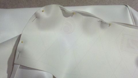 1900 Ford C-350 (Centurion Conversions) - A close-up view of white fabric, possibly upholstery, held in place with pins, with a Supermotors logo in the corner.