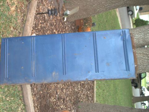 1971 Ford Bronco - A blue tailgate is shown outdoors, supported by logs and surrounded by grass and trees.