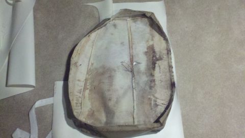 1900 Ford C-350 (Centurion Conversions) - A dirty and worn seat cushion is shown from the underside, lying on a flat surface.