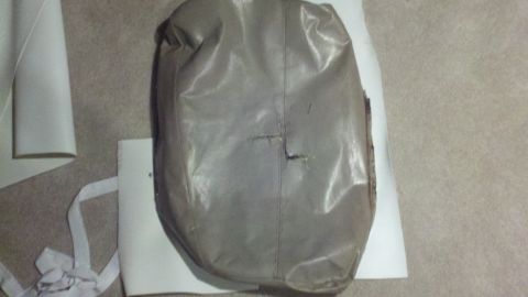 1900 Ford C-350 (Centurion Conversions) - A damaged gray car seat cover is shown next to white material on a carpeted floor.