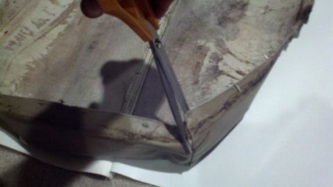 1900 Ford C-350 (Centurion Conversions) - Scissors are used to cut a damaged fabric interior panel, revealing underlying material and construction.