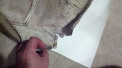 1900 Ford C-350 (Centurion Conversions) - A hand holds a piece of aged leather and canvas material, possibly a car interior part.