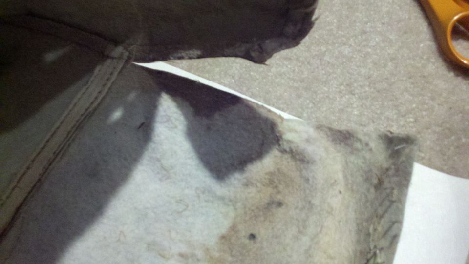 Close-up of stained fabric with stitching, next to orange-handled scissors