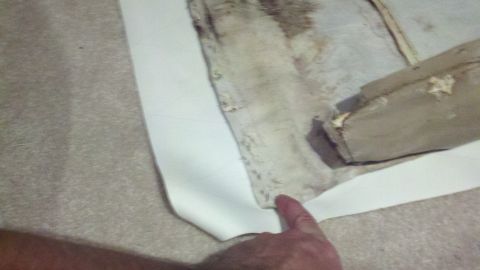 1900 Ford C-350 (Centurion Conversions) - Close-up view of worn interior upholstery and carpet, with a finger indicating a specific area.