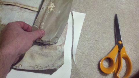 1900 Ford C-350 (Centurion Conversions) - Someone is preparing to cut fabric with scissors, possibly for upholstery repair.