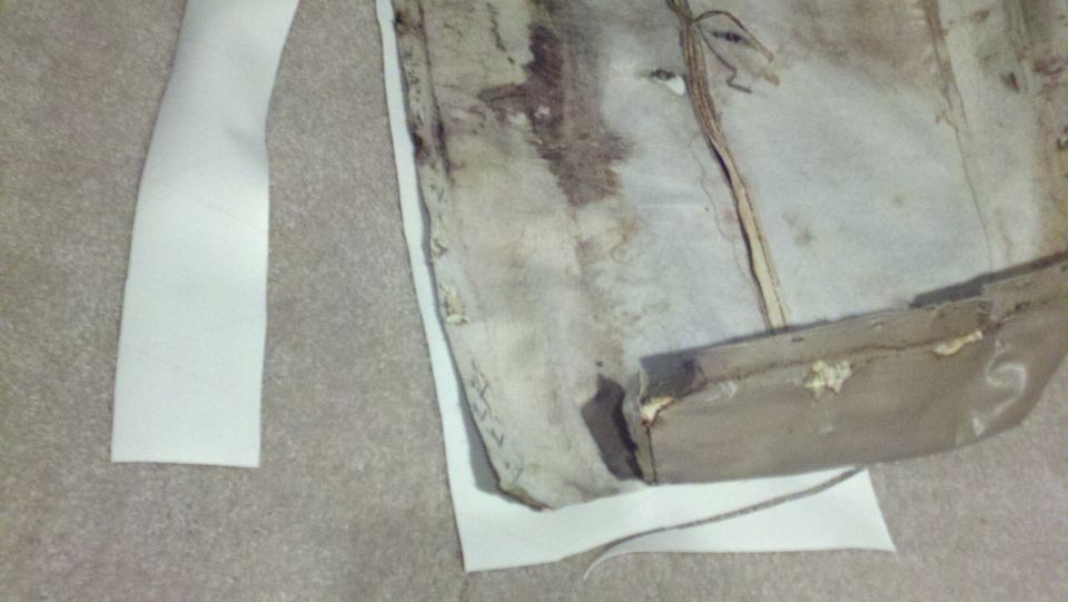 Worn, stained upholstery and white trim pieces on a carpeted surface