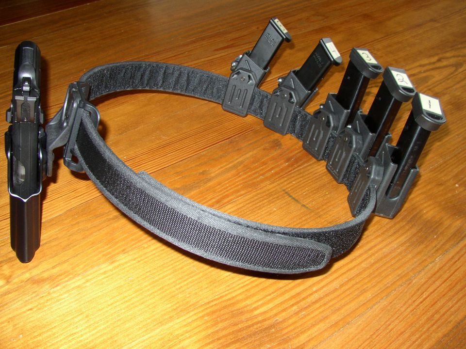 Pistol in a holster on a belt with four spare magazines