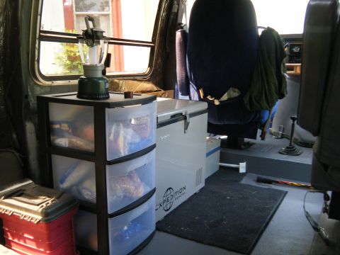 1988 Ford E350 - The interior of a van is outfitted with storage drawers and a portable cooler, suggesting a mobile living or working setup.